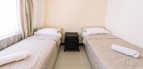 two beds in a room with a table between them at Gonzales Transient House in Baguio