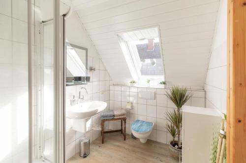 La salle de bains blanche est pourvue d'un lavabo et de toilettes. dans l'établissement Herzlich Willkommen auf unserem Hof!, à Ladbergen
