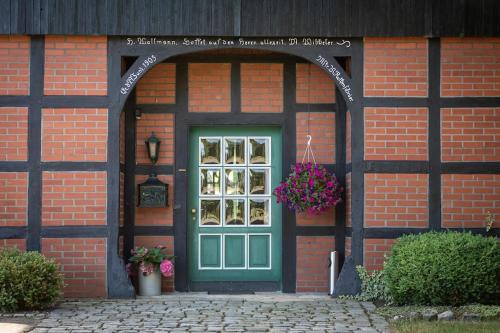 ceglany budynek z zielonymi drzwiami i oknem w obiekcie Herzlich Willkommen auf unserem Hof! w mieście Ladbergen