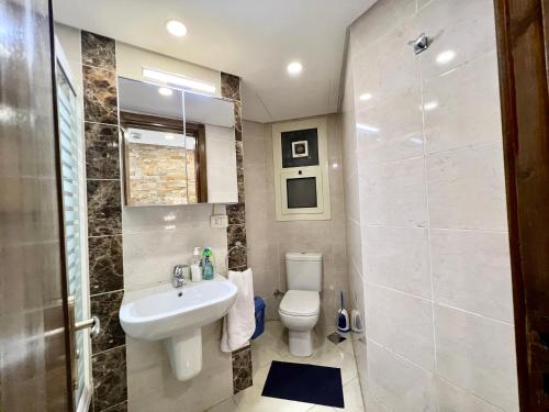 a bathroom with a white toilet and a sink at Luxury hotel apartment with pools in front AUC in Cairo