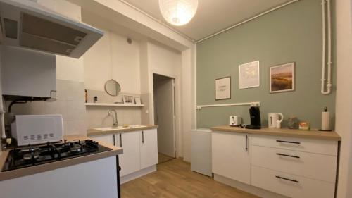 une cuisine avec des armoires blanches et un four à plaques de cuisson dans l'établissement Joyau caché nivernais, à Nevers