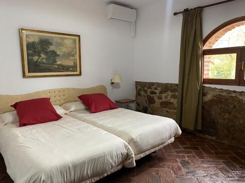 a bedroom with two beds and a window at Casas Rurales Monasterio de Rocamador in Almendral