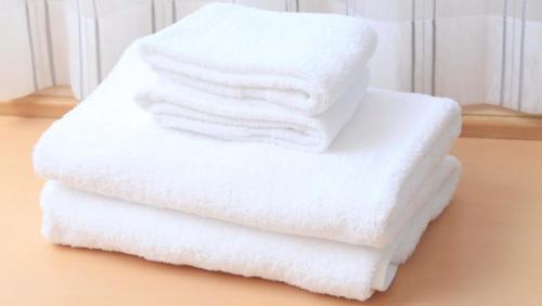 una pila de toallas blancas sentadas en una mesa en Richmond Hotel Hamamatsu en Hamamatsu