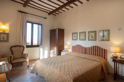 a bedroom with a bed and a chair and a window at Hotel Umbra in Assisi