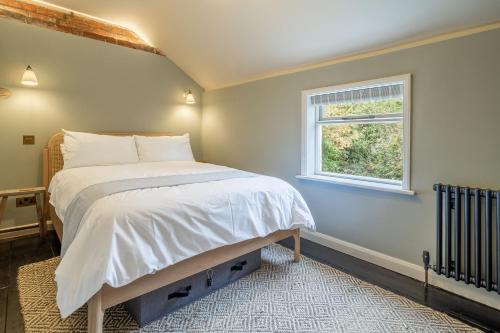 a bedroom with a large bed with a window at Tipple Cottage in Peasenhall