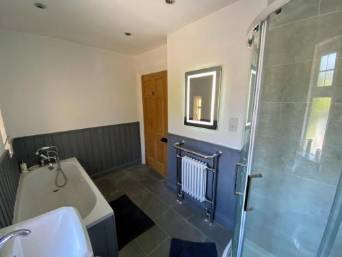 a bathroom with a shower and a sink and a tub at Glaisters Farmhouse in Castle Douglas