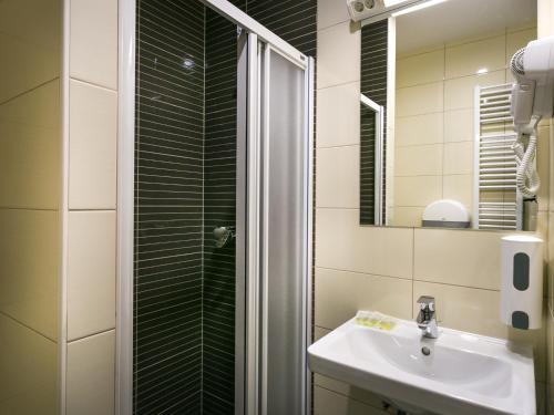 a bathroom with a shower and a sink and a mirror at Hostel Moving in Zagreb