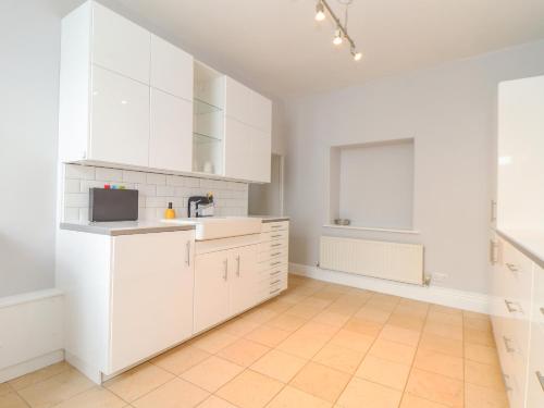 a white kitchen with white cabinets and a sink at Castle View in Marazion