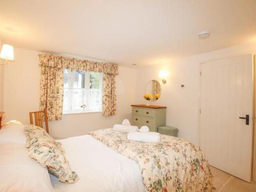 a bedroom with two beds and a window at Mill Cottage in Upwey