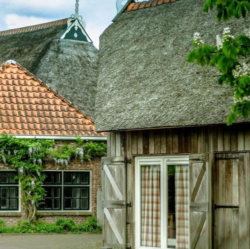 un vecchio fienile con una porta e un tetto di Teades Plak bij De Herberg van Smallingerland a Rottevalle
