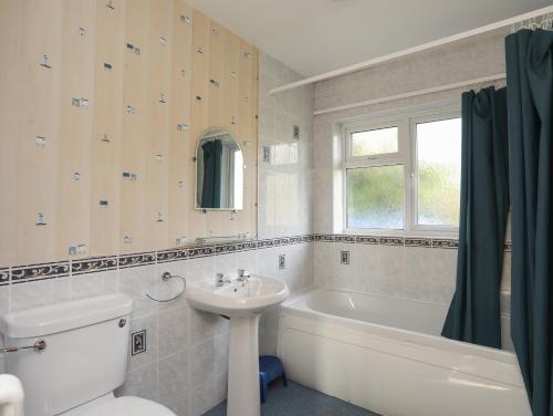 a bathroom with a sink and a toilet and a bath tub at 14 Cae Pin in Pwllheli