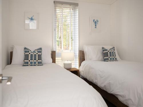 two beds in a room with white walls and a window at Murmur y Coed in Llanfairpwllgwyngyll