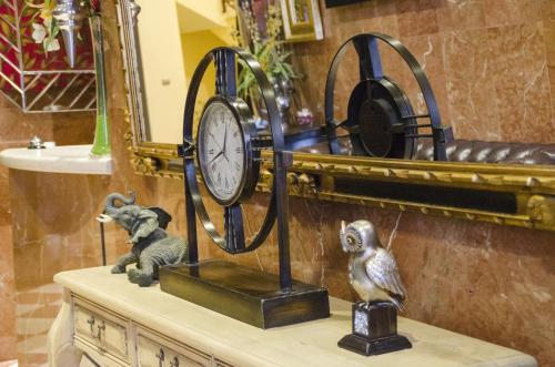 a clock on top of a table with a monkey statue at Hotel Duquesa in Seville