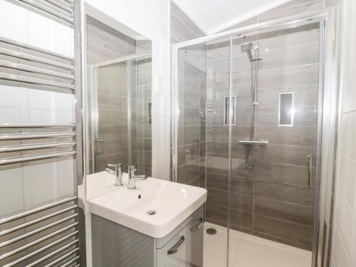 a white bathroom with a sink and a shower at The Gallops in Chipping Norton