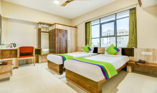 1 dormitorio con 2 camas, lavabo y ventana en The Tripti Hotel & Banquets, en Indore