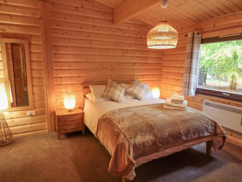 a bedroom with a bed in a log cabin at Leafy Hollow Lodge in Louth