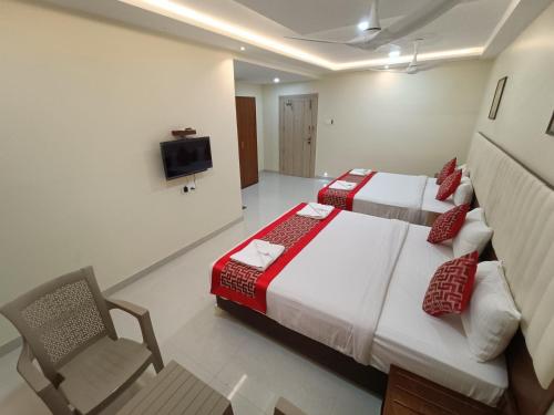 sypialnia z 2 łóżkami, krzesłem i telewizorem w obiekcie Sri Aswin Grand w mieście Nāmakkal