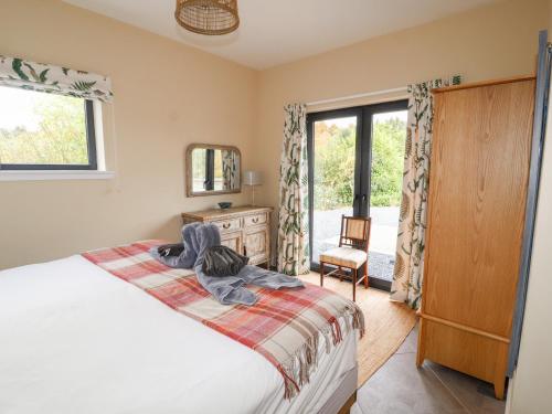 a bedroom with a bed and a dresser and a window at The Lodge in Stranraer