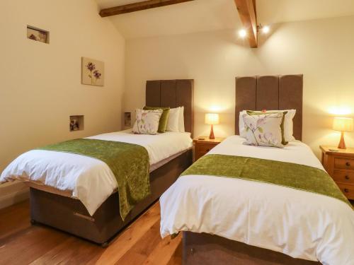 two twin beds in a room with wooden floors at Mosscarr Barn in Harrogate