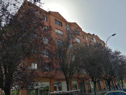a red brick building with trees in front of it at Andramari Tourist Home Parking& wifi in Amorebieta-Etxano
