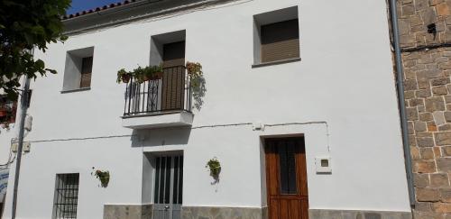 a white building with windows and a door at La Casa del Muro in El Bosque