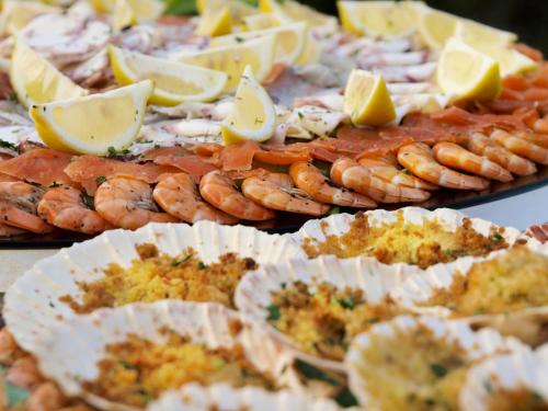 a table topped with plates of food with shrimp and lemon slices at Hotel Villa Rosa in Nago-Torbole