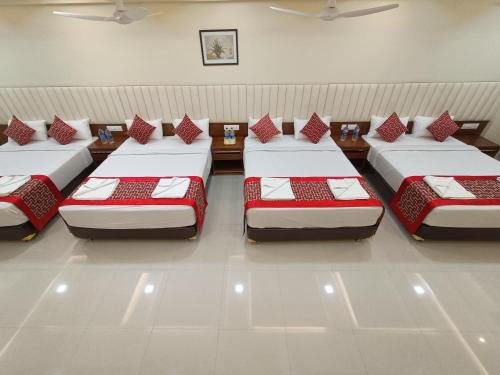 a row of four beds in a room at Sri Aswin Grand in Nāmakkal