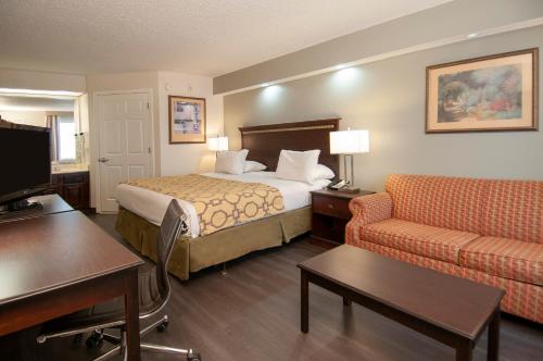 a hotel room with a bed and a couch at Baymont by Wyndham Tuscaloosa in Tuscaloosa