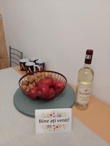 eine Flasche Wein und ein Obstkorb auf dem Tisch in der Unterkunft 1st Apartment in Nehoiu