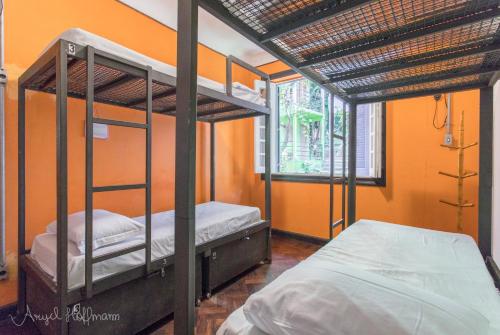 two bunk beds in a room with an orange wall at Pura Vida Hostel in Rio de Janeiro