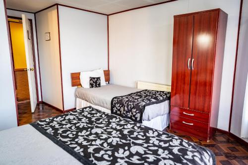プエルト・ナタレスにあるHostal Alcázarのベッド2台とキャビネット付きのホテルルームです。