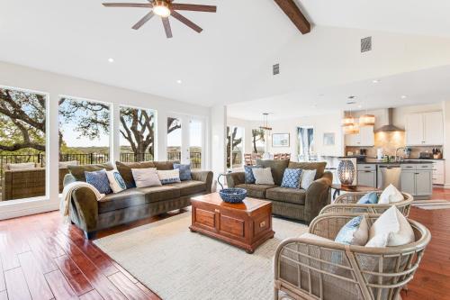 a living room with couches and chairs and a kitchen at Cliff side Oasis in Spicewood