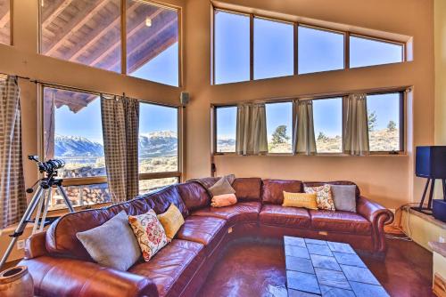 a living room with a leather couch and large windows at Luxe Twin Lakes House with Mountain and Lake Views! in Twin Lakes