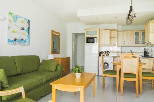 ベナルマデナにあるBenalbeach Sea Frontのリビングルーム(緑のソファ付)、キッチンが備わります。