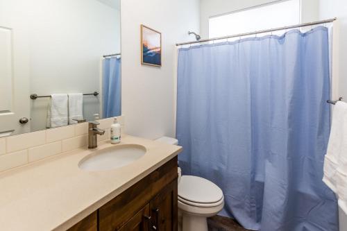 a bathroom with a sink and a blue shower curtain at Tamarack Trails Bungalow in Donnelly
