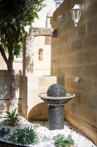 a stone bird bath in front of a building at Bliss Boutique Living in Xagħra