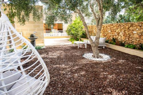 una hamaca blanca en un jardín con un árbol en Bliss Boutique Living, en Xagħra