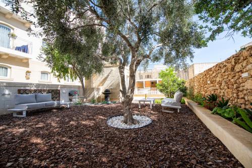 einen Innenhof mit einem Baum und zwei Sofas und einem Gebäude in der Unterkunft Bliss Boutique Living in Xagħra