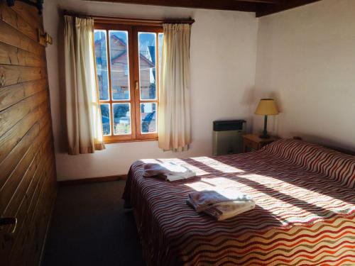 een slaapkamer met een bed met twee handdoeken erop bij Cabañas Chapelco in San Martín de los Andes