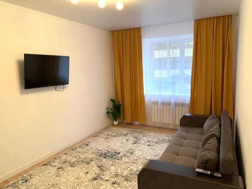 a living room with a couch and a flat screen tv at Scandi Home in Uralsk