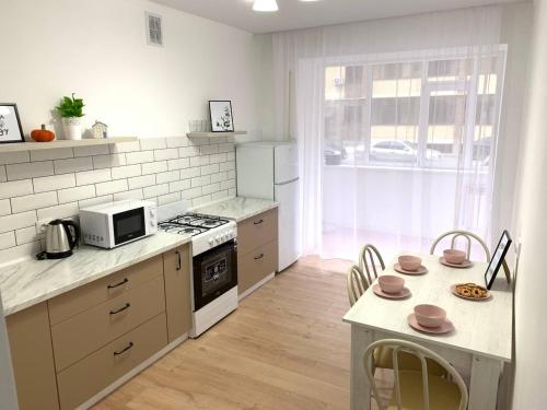 a kitchen with a stove and a table with chairs at Scandi Home in Uralsk