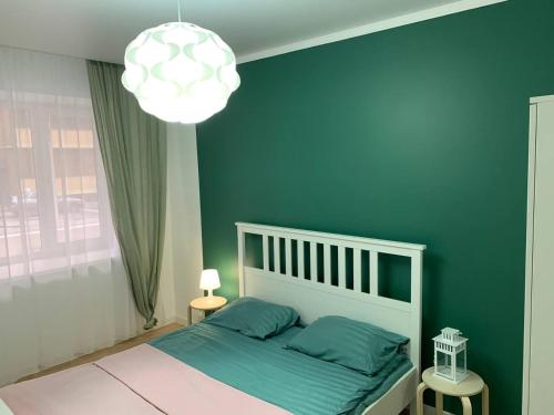 a bedroom with a white bed and a green wall at Scandi Home in Uralsk