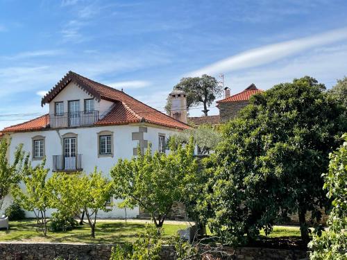 une maison blanche avec un toit rouge et des arbres dans l'établissement Casa das Quintas, à Quinta das Quebradas