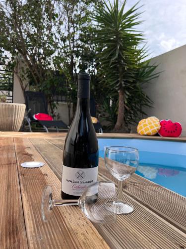 una botella de vino en una mesa de madera con una copa en Charmante maison Climatisée avec piscine au Calme à Carcassonne, en Carcassonne