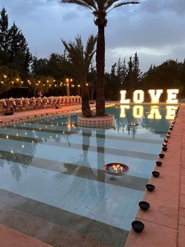 a swimming pool with a sign that reads love love crore at LES JARDINS DE MARRAKECH in Marrakech