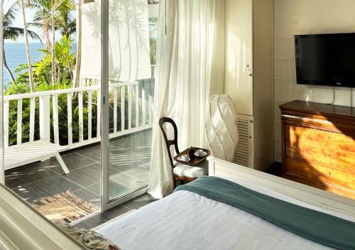 1 dormitorio con 1 cama y balcón con TV en Lovely house with private beach, en Santa Bárbara de Samaná