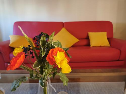 eine rote Couch mit gelben Kissen und eine Vase mit Blumen in der Unterkunft Nonna Mary's Apartment - Vicino Pala Alpitour in Turin