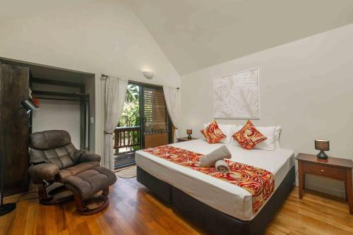 een slaapkamer met een kingsize bed en een stoel bij Cook Islands Holiday Villas - Turtle Villa in Arorangi