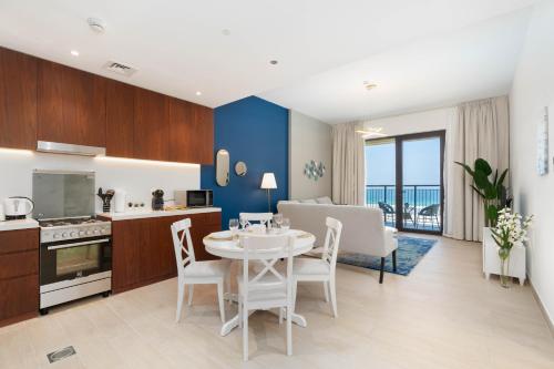 a kitchen and living room with a table and chairs at Ultimate Stay / 4 People / Beachfront / Sea View / Balcony Sunset / Brand New / La Mer in Dubai