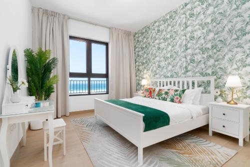 a bedroom with a white bed with a green blanket at Ultimate Stay for 4 with Sunset Balcony at La Mer in Dubai